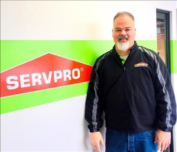 Keith Whalen standing in front of a white and green wall with the SERVPRO logo on it.