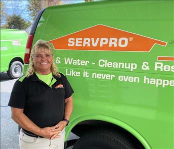 Female employee Pam Butts standing in front of a SERVPRO vehicle.