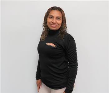 Female employee Norma Ortiz standing in front of a muted wall
